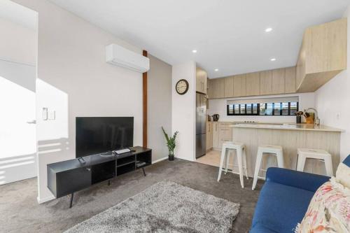 a living room with a blue couch and a kitchen at Lovely Tauranga 2 Bed Home in Tauranga