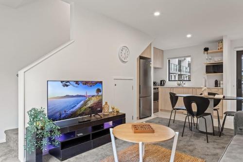 a living room with a large tv and a kitchen at Charming 2 Bed Family Home in Auckland