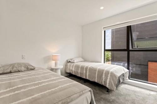 a bedroom with two beds and a large window at Charming 2 Bedroom Family Home in Auckland