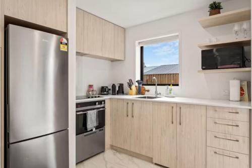 a kitchen with a stainless steel refrigerator and a window at Charming 2 Bedroom Family Home in Auckland