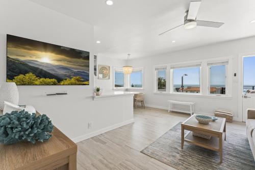 a white living room with a large painting on the wall at Penthouse Steps from Victoria Beach 180 degree ocean views in Laguna Beach