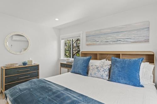 a bedroom with a bed with blue pillows and a window at Penthouse Steps from Victoria Beach 180 degree ocean views in Laguna Beach