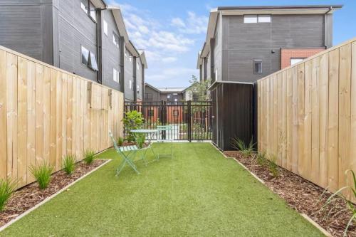 a backyard with a fence and a table and chairs at Vibrant 2 bed Henderson Abode in Auckland