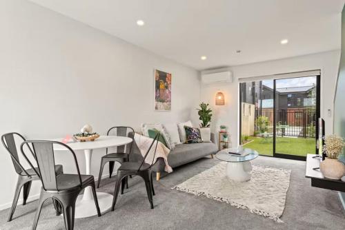 a living room with a couch and a table and chairs at Vibrant 2 bed Henderson Abode in Auckland