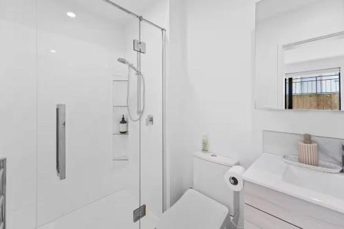 タウランガにあるStylish Tauranga Homeのシャワーと洗面台を備えた白いバスルーム