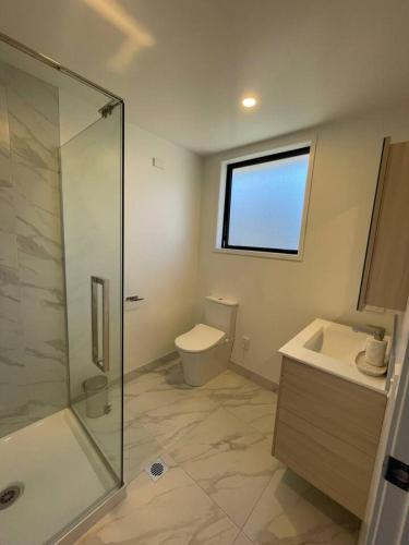 a bathroom with a shower and a toilet and a sink at Stylish 1 Bed 1 Bath Retreat in Auckland