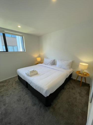 a bedroom with a large white bed with a window at Stylish 1 Bed 1 Bath Retreat in Auckland