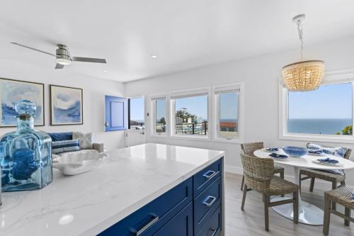 a kitchen with blue cabinets and a table and chairs at Penthouse Steps from Victoria Beach 180 degree ocean views in Laguna Beach