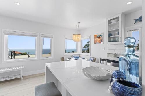 a white kitchen with a large glass bottle on a counter at Penthouse Steps from Victoria Beach 180 degree ocean views in Laguna Beach