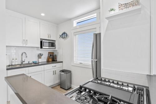 a kitchen with white cabinets and a stove top oven at Ocean VIEWS Steps from Victoria Beach Lux Design in Laguna Beach