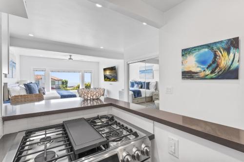 a kitchen with a stove top oven next to a living room at Ocean VIEWS Steps from Victoria Beach Lux Design in Laguna Beach