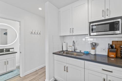 a white kitchen with a sink and a microwave at Ocean VIEWS Steps from Victoria Beach Lux Design in Laguna Beach