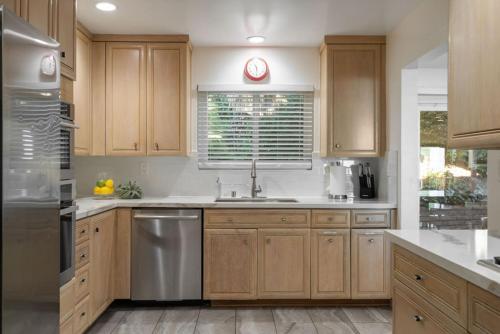 a kitchen with wooden cabinets and stainless steel appliances at Overlooking Luxury - Pool Heat - Spa - Games in Pico Rivera