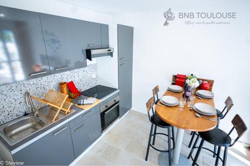 - une cuisine avec une table et des chaises en bois dans l'établissement BNB TOULOUSE - Refuge urbain - Clim - Terrasse - Parking - WiFi - Proche transports, à Toulouse