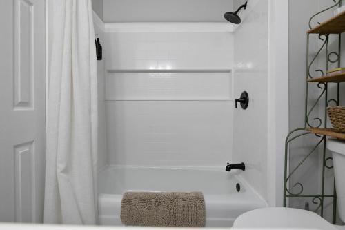 a white bathroom with a tub and a shower at Cozy Carolina in Fayetteville