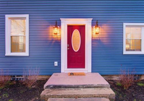 a blue house with a red door and two windows at Sleeps 16 Large Groups 2 Full Homes In Vermilion in Vermilion