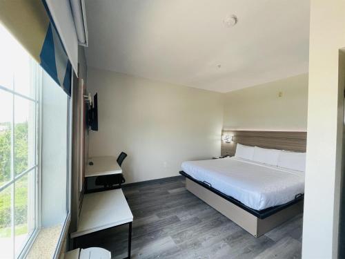 a hotel room with a bed and a window at Sonesta Essential North Houston in Houston