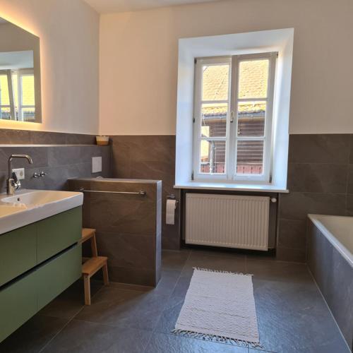 a bathroom with a sink and a tub and a window at Haus am Bach in Fischbachau