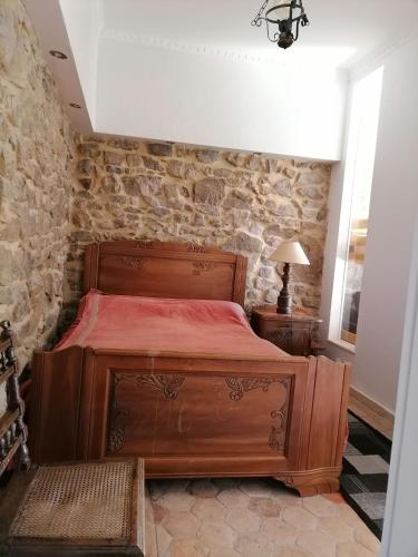 a bedroom with a wooden bed and a stone wall at Edelweiss in Roussillon-en-Morvan