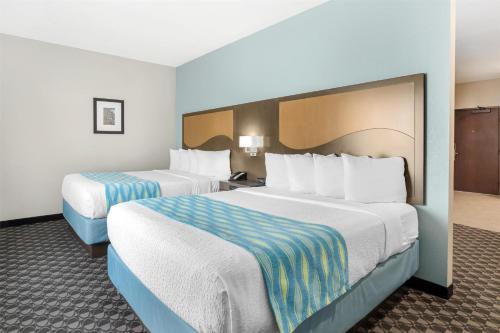 two beds in a hotel room with white sheets and blue accents at Best Western Plus Waller Hotel in Waller