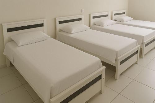 Tres camas en una habitación con paredes blancas. en Alto Serra Hotel, en Campina Grande