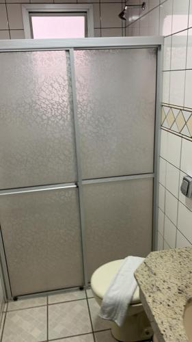 a shower stall in a bathroom with a toilet at Goldmen Business Criciúma in Criciúma