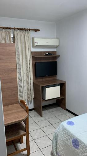 a room with a tv and a bed and a table at Goldmen Business Criciúma in Criciúma
