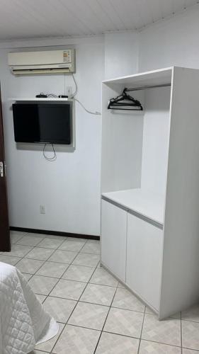 a room with a tv and a white wall at Goldmen Business Criciúma in Criciúma