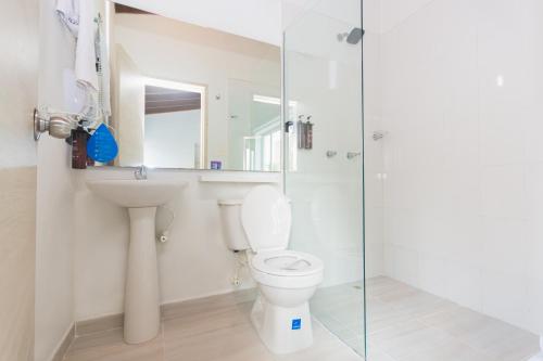 a bathroom with a toilet and a glass shower at Hotel Suite del Parque in Medellín