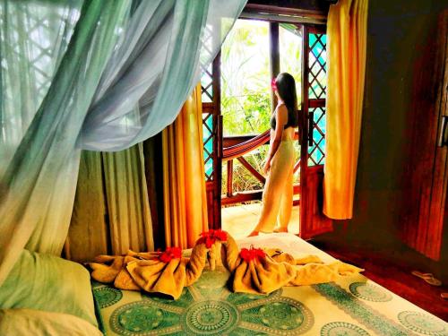 a woman standing in a bedroom looking out the window at Ocean Forest Ecolodge in San Pedrillo