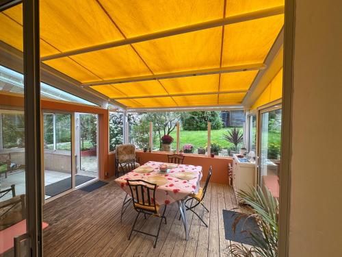 une véranda avec une table et des chaises dans l'établissement Maison familiale à Morgat, jardin clos, à 2 minutes de la plage, à Crozon