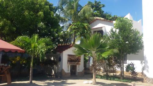 a white house with palm trees in front of it at Luciano & Grace Apartments in Watamu