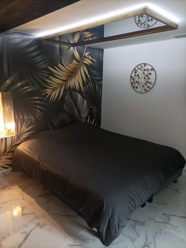 une chambre avec un lit noir avec un mur feuillu dans l'établissement Love Room, L'aubertine, à Putanges