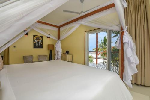 a bedroom with a white bed and a balcony at Alma Boutique Hotel in Jambiani