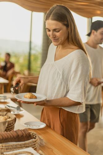 a woman holding a plate of food on a table at Pousada Boutique Villa Valley in Praia do Rosa