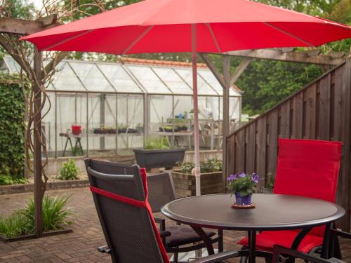 a table and chairs with a red umbrella on a patio at Vakantiehuisjes "De Veldzijde" in Losser