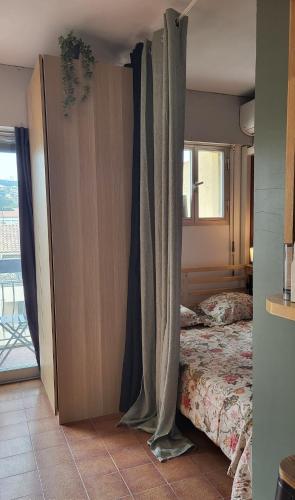 - une chambre avec un lit avec des rideaux et une fenêtre dans l'établissement Joli studio 2 pas du port, clim et au calme, à Bandol