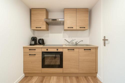 une cuisine avec des armoires en bois et un évier dans l'établissement Studio Navarre Calm and comfort at La Mulatière, à La Mulatière