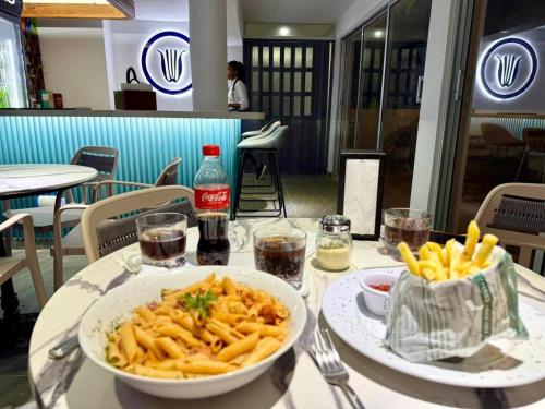 a table with a bowl of pasta and french fries at Hotel Neptuno Refugio in Boca Chica