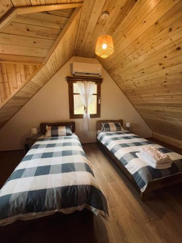 two beds in a room with wooden ceilings at Oak House Mrežnica in Duga Resa
