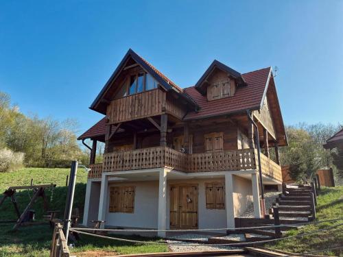 a wooden house with wooden doors and a balcony at Oak House Mrežnica in Duga Resa