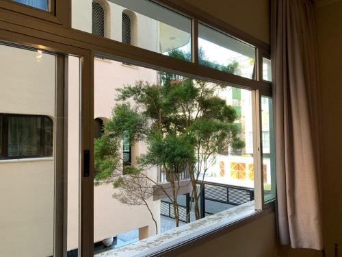 a window in a room with a view of a tree at Apê Retrô com Wi-Fi e Vaga - 350 m da Praia da Enseada in Guarujá