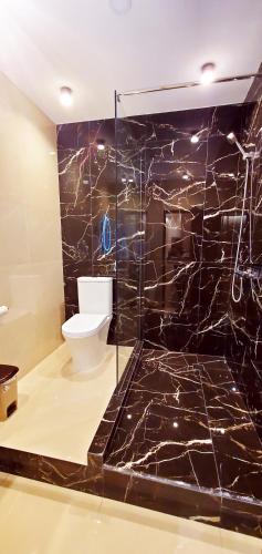 baño con aseo y pared de mármol negro en Уют, en Balaovit