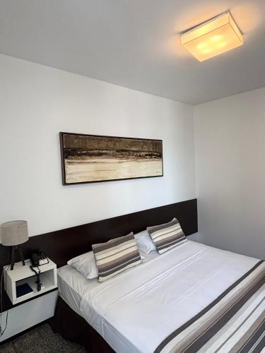 a bedroom with a bed with white sheets and pillows at Hotel Brasil Tropical in Fortaleza
