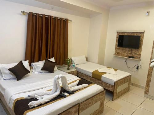 a hotel room with two beds and a television at L A V Mansion in Bengaluru