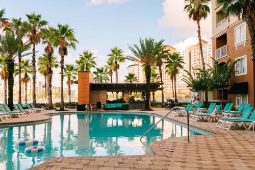 a swimming pool with chairs and palm trees at The Point Universal by Edge near Epic in Orlando