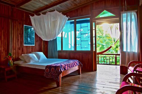 a bedroom with a bed and a large window at Ocean Forest Ecolodge in San Pedrillo
