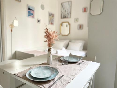 une table de salle à manger avec deux assiettes bleues et un vase dans l'établissement Cocon Montmartre - Netflix, Fibre & Conciergerie, à Paris