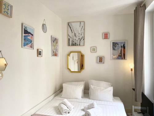 une chambre avec un lit avec des draps blancs et un miroir dans l'établissement Cocon Montmartre - Netflix, Fibre & Conciergerie, à Paris