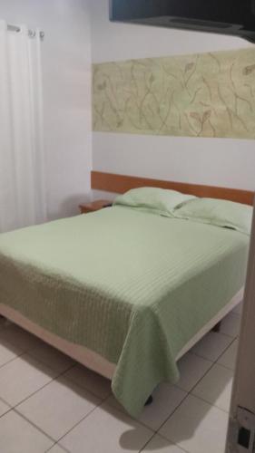 a bedroom with a bed with a green blanket on it at BOA VIAGEM PROX AO MAR in Recife